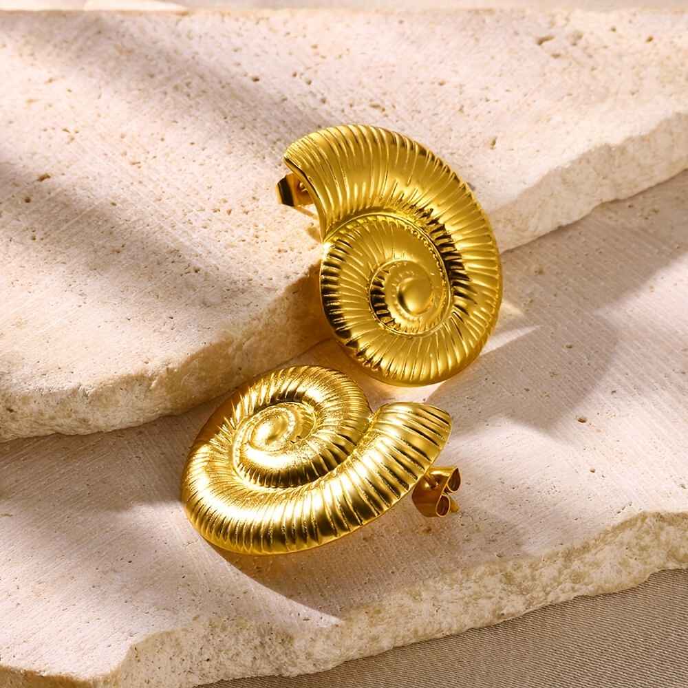 d03e5152-a900-4742-acc5-3cfbc12b44d5_1_11zon Photo de boucles d'oreilles en spirale dorée, fabriquées en acier inoxydable, présentées dans un écrin en velours blanc.