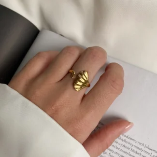 Photo d'une bague dorée ajustable avec un motif de feuille de ginkgo, fabriquée en acier inoxydable, sur fond blanc.