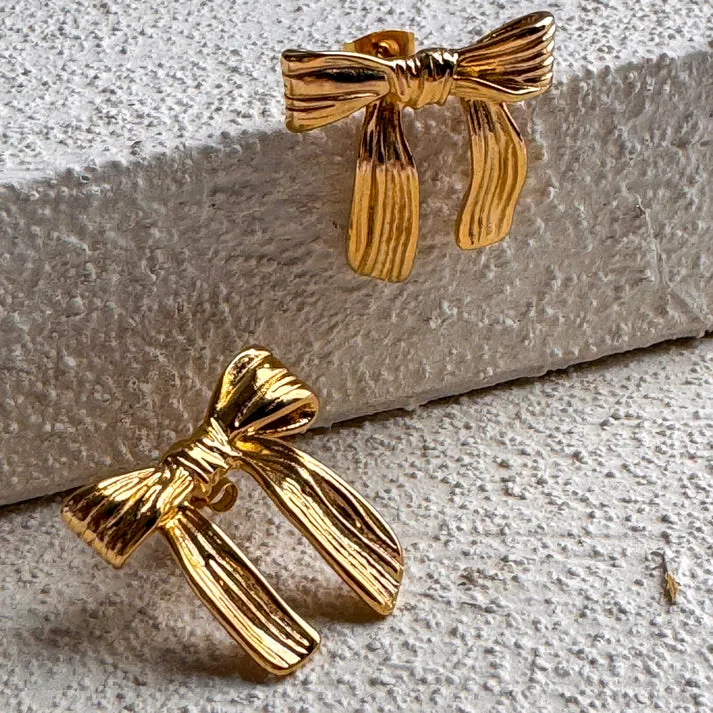 boucles-noeud-dore-acier-inoxydable.jpg (2) Photo de boucles d'oreilles dorées en forme de nœud, fabriquées en acier inoxydable, sur fond blanc.