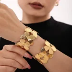 Photo d'un bracelet manchette doré avec un motif de papillons entrelacés, fabriqué en acier inoxydable, sur fond blanc.