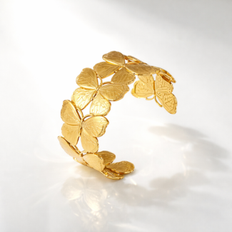 Photo d'un bracelet manchette doré avec un motif de papillons entrelacés, fabriqué en acier inoxydable, sur fond blanc.