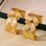 Photo d'un bracelet manchette doré avec un motif de papillons entrelacés, fabriqué en acier inoxydable, sur fond blanc.