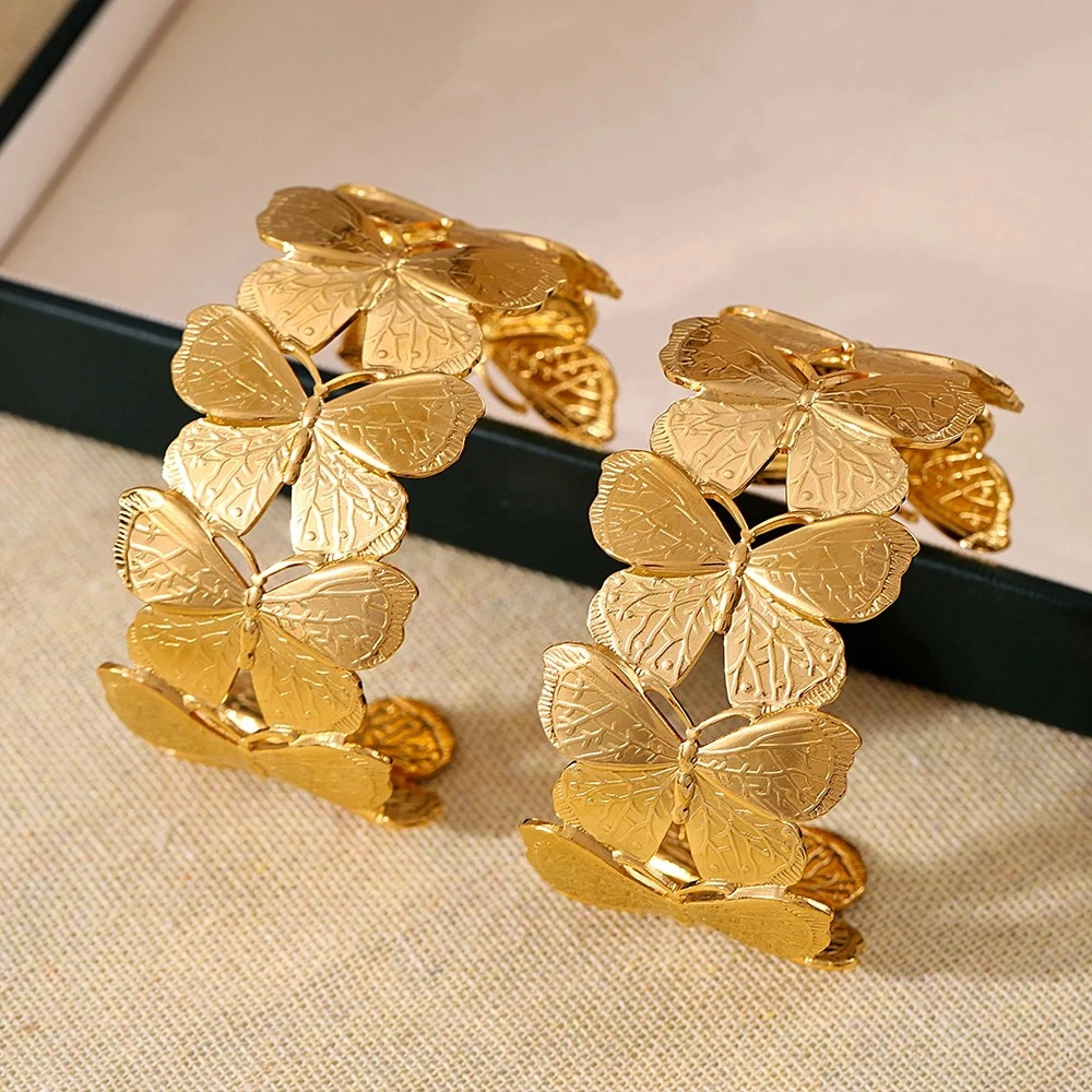 Photo d'un bracelet manchette doré avec un motif de papillons entrelacés, fabriqué en acier inoxydable, sur fond blanc.